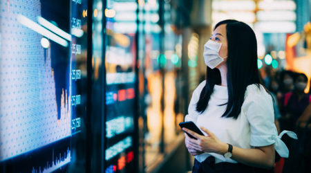 A lady wearing a mask looking at stocks