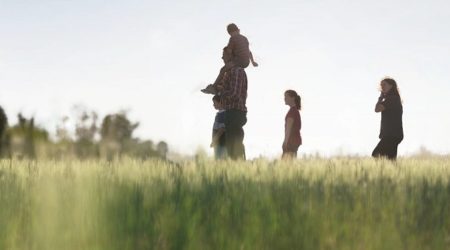 Image of a family of four in a field (two parents and two children)