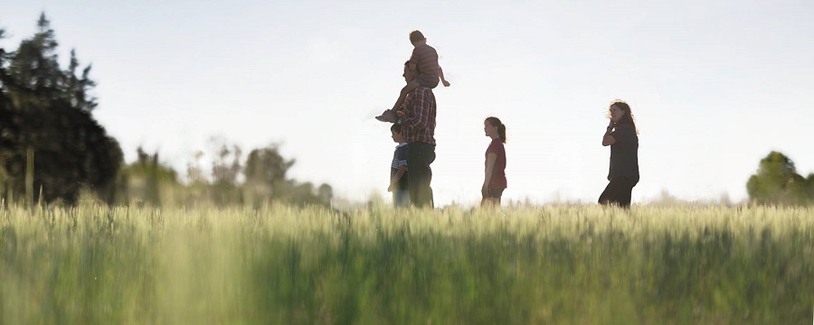 Image of a family of four in a field (two parents and two children)